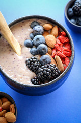 Healthy blueberry smoothie bowl on blue background