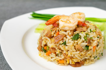 Fried rice with shrimp and Chinese sausage in white plate on concrete table.