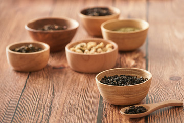 assortment of dry tea in white bowls on wooden surface