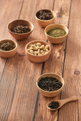 assortment of dry tea in white bowls on wooden surface