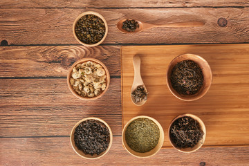 assortment of dry tea in white bowls on wooden surface