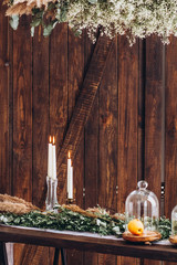 white tall candles in crystal candlesticks. candles on aged rustic wooden textured background. Place for text. autumn still life