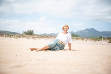 Naklejka na ściany i meble Beautiful mature woman posing on the beach