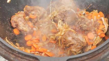 Real Uzbek pilaf in a huge cauldron. Cooking national dishes. Traditional pilaf cooking. Preparation of national dishes