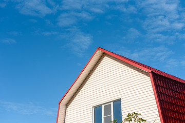 Blue sky with clouds and the roof of a country house