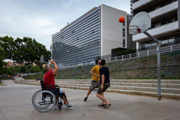 three boys, one of them in a wheelchair playing basketball