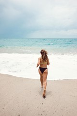 Fototapeta premium Girl running by the shore towards the water