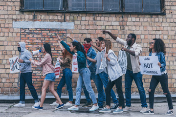 Fototapeta premium multicultural people walking near brick wall during protest