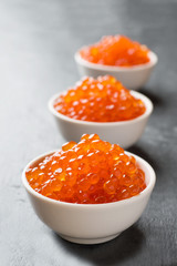 red salmon caviar in a plate on a dark table.