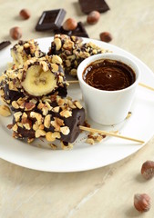 Frozen banana in chocolate and hazelnuts, vertical 