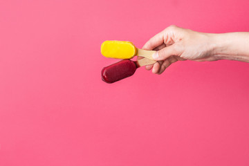 Young caucasian woman girl holds in hand two frosty ice cream pops popsicles on wooden stick on fuchsia pink background. Summer desserts sweet homemade treats fun concept. Poster with copy space