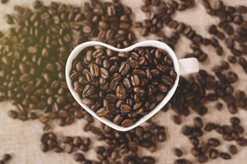 directly above view a heart shape mug of a raw roasted coffee beans. Concept of Favorite drink and coffee addiction