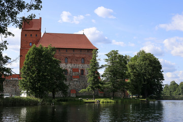 Trakai Island Castle, major tourist medieval attraction, reflecting in clear water of Galve lake. White clouds