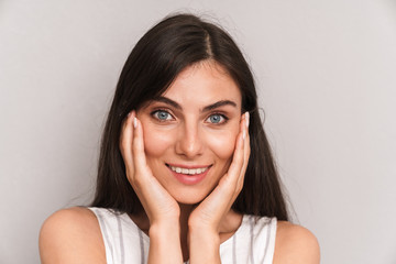 Image closeup of beautiful woman with long dark hair smiling and touching her cheeks