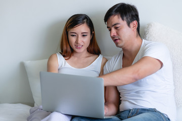 Pregnant woman in bed with man. Asian woman with white man. Using laptop. Mix race relationship concept. Trying to explain how it works.