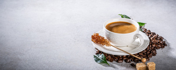 Coffee freshly brewed in a white cup with beans and leafs. Food background with copy space.