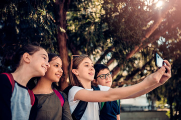 School kids sitting in the shade and taking selfie on the street