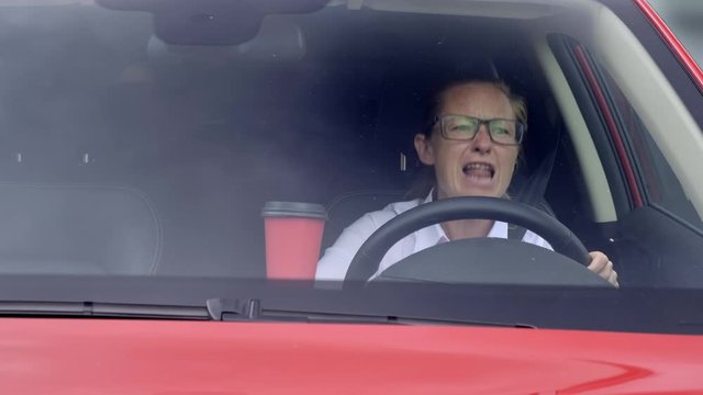 Business woman swears at wheel of car.