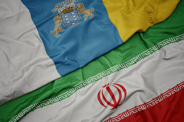 waving colorful flag of iran and national flag of canary islands.