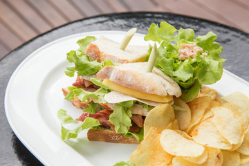 Photo of a british sandwich made with chicken, bacon, mango, tomato, cheese, and  french fries