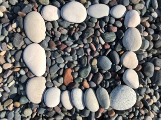 Background texture: mosaic of fine sea pebbles. Small pebbles lie exactly next to each other. Pebble frame on the seashore.