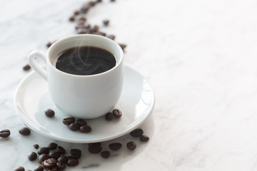 Hot cup of espresso or americano coffee in a traditional white cup on a table