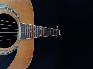 Obraz premium Part of an acoustic guitar on a black background. Six-string guitar, light wood color. String musical instrument. Classical guitar, close-up.