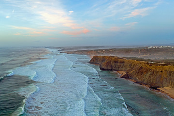 Aerial from the beach and ocean at Monte Clerigo in Portugal at sunset