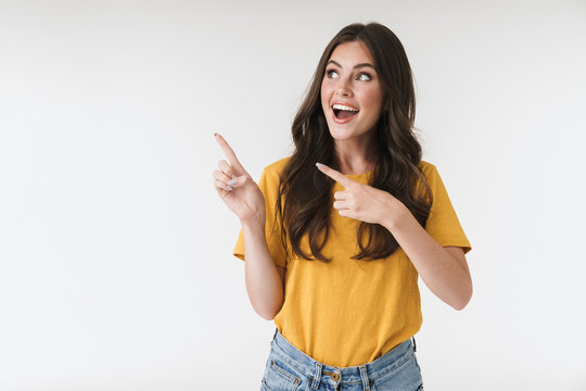 Image of charming brunette woman wearing casual clothes smiling and pointing fingers at copyspace