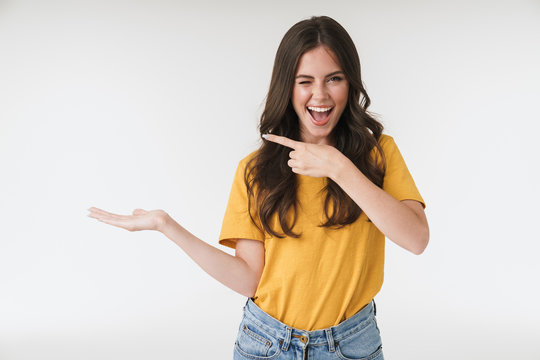 Image of beautiful brunette woman wearing casual clothes smiling and pointing fingers at copyspace on her palm