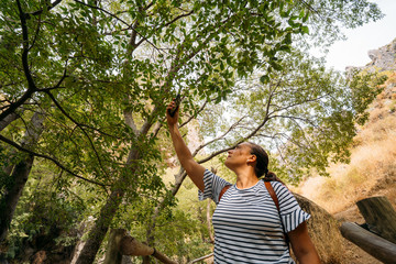 Woman with her mobile smart phone searching for reception signal in the forest.