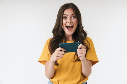 Image of pleased brunette woman wearing casual clothes laughing and using cellphone