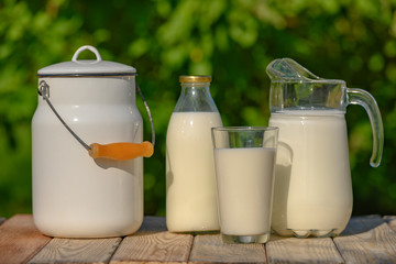 Glass and jug of fresh milk on wooden table