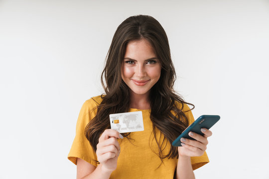 Image of charming brunette woman wearing casual clothes holding credit card and cellphone