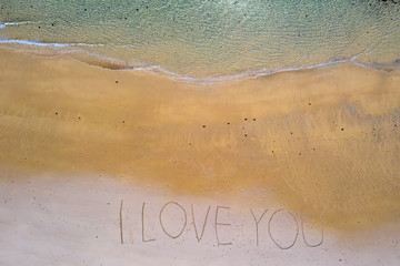 Aerial top shot from ocean waves and handwritten I love you at the beach