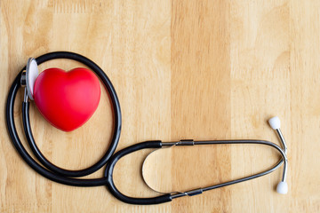 Red heart and  stethoscope on wooden table. Doctor tool for heartbeat listening. Healthcare concept. Empty place for text,