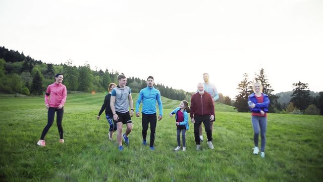 Large group of people cross country jumping in nature at sunset.