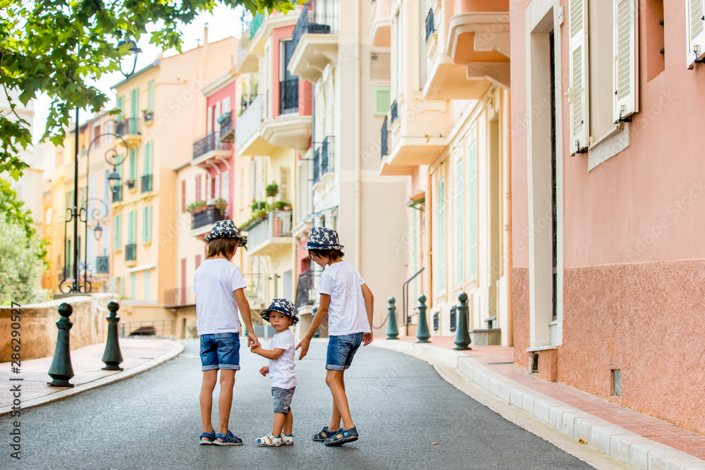 Sticker Children walking on a narrow street with houses in Monaco-Ville, Monaco on a cloudy day