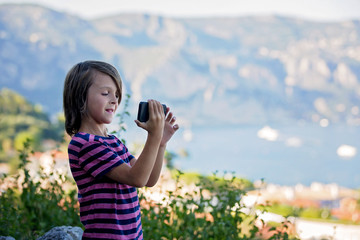 Fototapeta premium Preteen child, taking pictires with mobile of view on French Riviera