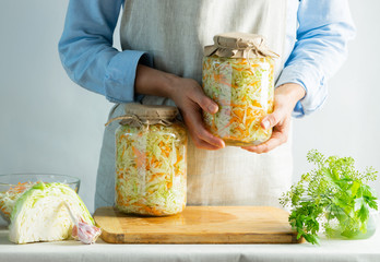 Fermentation preservation Sauerkraut in glass jars in the hands of a woman natural background....