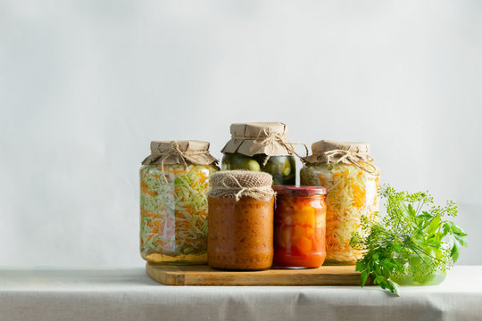 Fermented preserved or canning various vegetables zucchini sauerkraut carrots cucumbers in glass jars on table