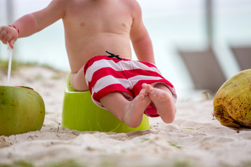 Little toddler boy, learning potty training on the beach on a tropical island