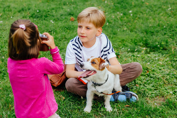 Cute clever little girl photographing handsome blond older boy