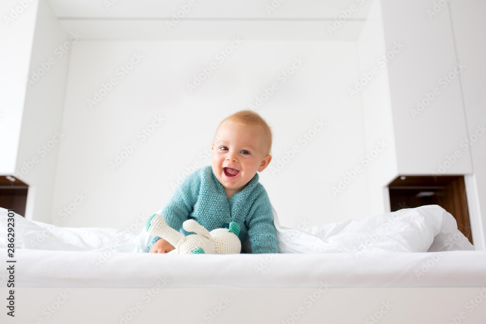 Canvas Prints Little cute baby boy, child in knitted sweater, holding knitted toy, smiling happily at camera