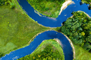 Top view drone shot of a green field, forest and river