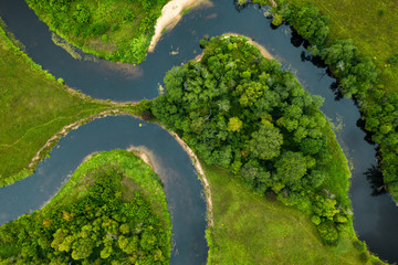 Top view drone shot of a green field, forest and river