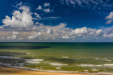Peaceful sea and cloudy blue sky. Horizon line. Sand beach.