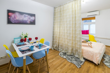 Spaceous bedroom with served table. Zoning with curtains.