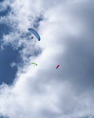 A group of three Parachouttes going side to side in the blue sky with clouds in the French Alps, Chamonix during a summer tour, fly and sport.