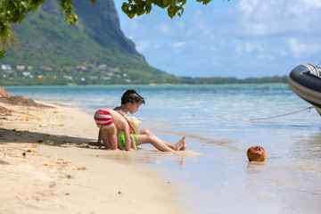 Sweet child, sit on the shore on the beach with coconut, enjoying beautiful day on le morne island